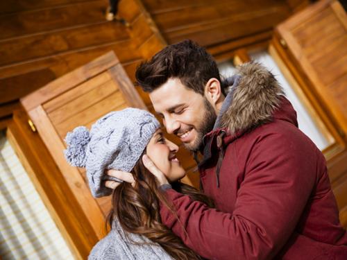 Paar, welches sich vor einem Ferienhaus umarmt